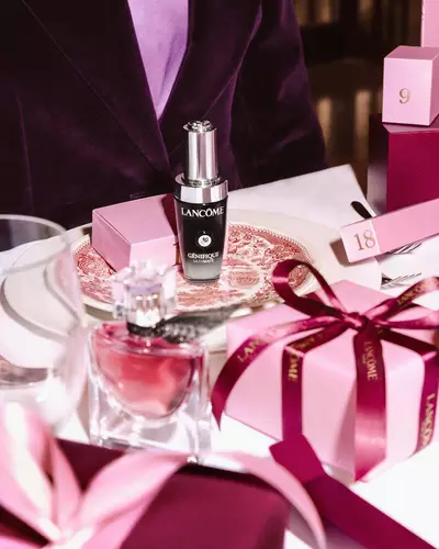 Lancome kozmetički proizvodi i ružičaste poklon-kutije aranžirani na svečanom blagdanskom stolu.