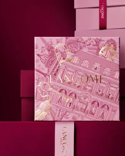 Elegantno složene ružičaste i tamnocrvene Lancome poklon-kutije, s naglaskom na središnju kutiju ukrašenu zlatnim ilustracijama pariške arhitekture.