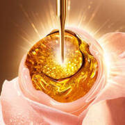 Zlatna esencija kaplje iz pipete na ružičasto cvijeće, simbolizirajući prirodnu ljepotu i njegu.