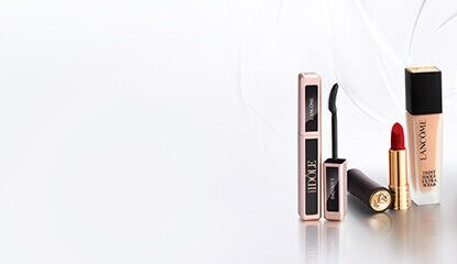 A minimalist display of Lancome perfume bottles arranged on white boxes against a light background.