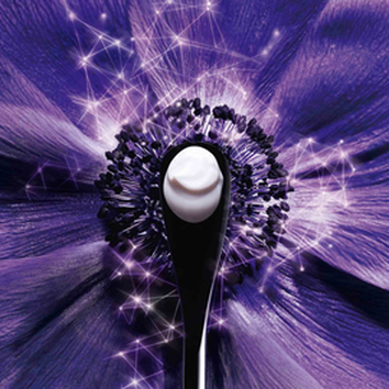 Mračna ljubičasta cvijet s crnom žlicom i kremastim sadržajem u središtu, okružen blistavim uzorcima.