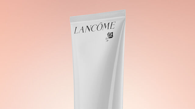 A Lancome skincare product displayed against a soft, warm gradient background.